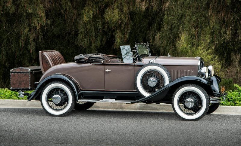 Vintage sepia-toned image of a convertible sports car with low horizontal lines and geometric brickwork
